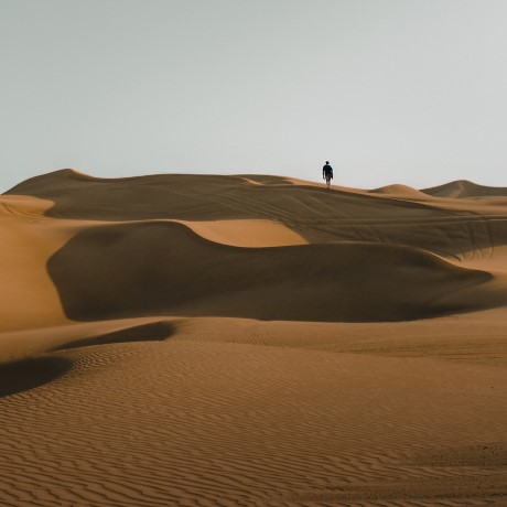 Silhouette of a person in the distance, walking in a desert. 