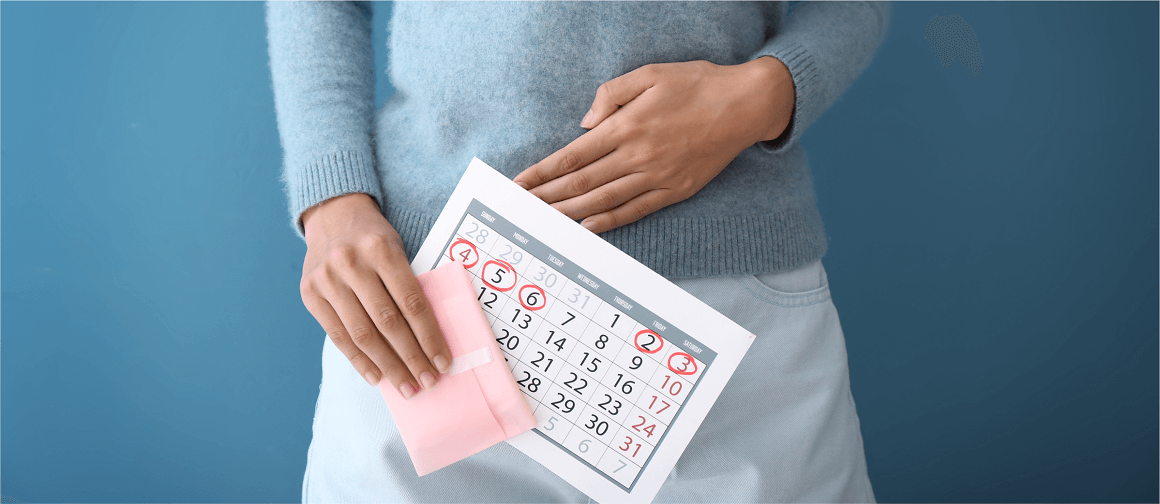 Woman touching her abdomen while holding a calendar and a sanitary napkin.