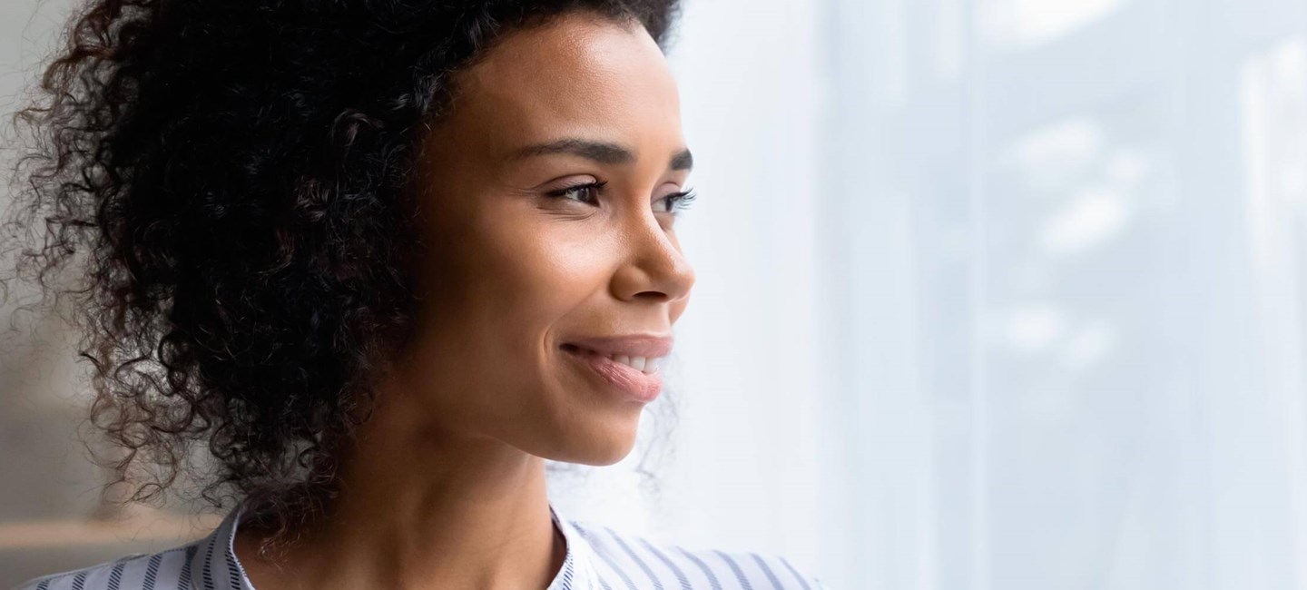 Stock photo of a woman looking through a window.