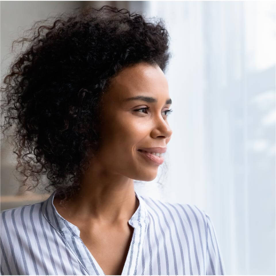 Stock photo of a woman looking through a window.