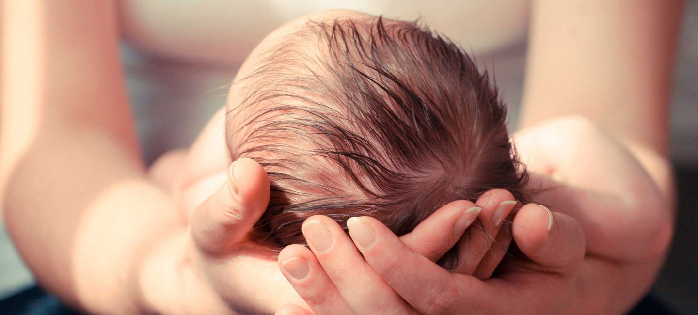 Newborn baby cradled in mothers arms