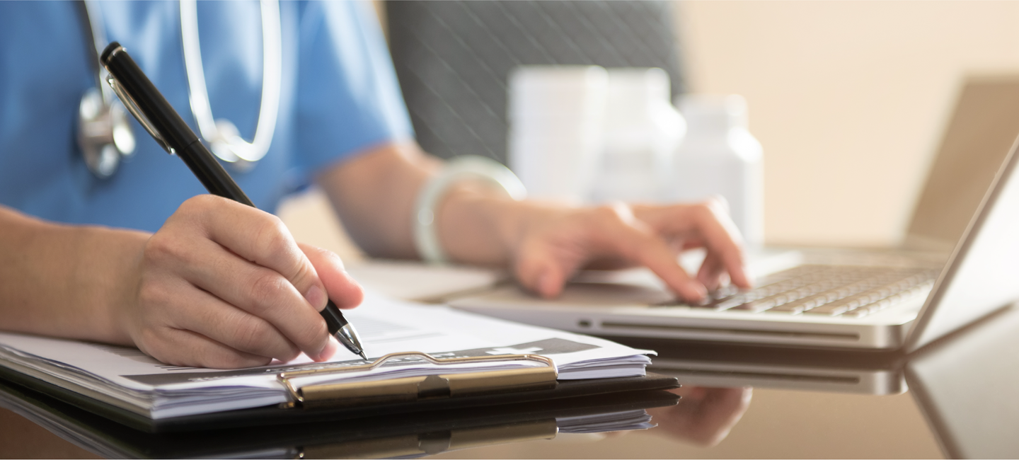 Photograph of a doctor filling out on a notepad.