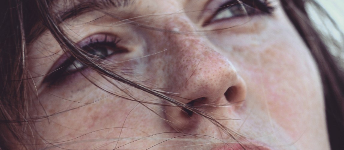 Close-up of woman’s face with strands of hair covering her face.