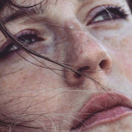 Close-up of woman’s face with strands of hair covering her face.