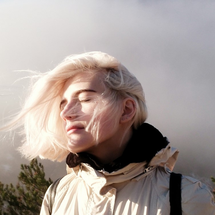 Young woman in nature with a relaxed expression, closed eyes with the sun on her face.